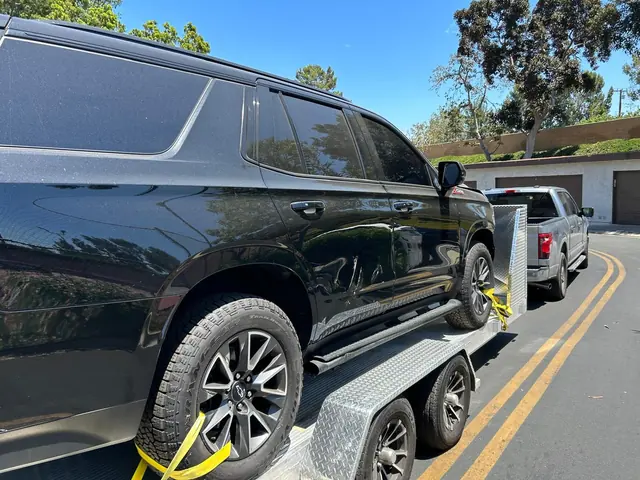 SUV negra asegurada en el remolque abierto de aluminio