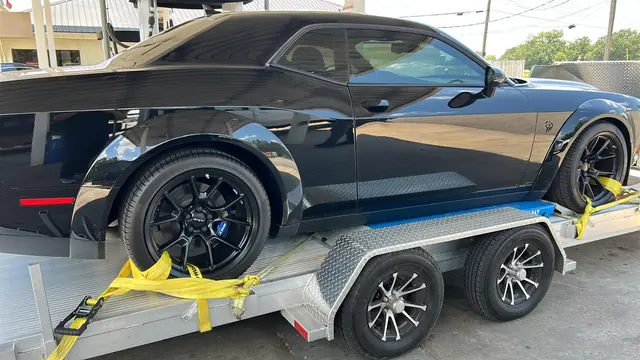Rueda de un Dodge Challenger amarrada en el remolque abierto